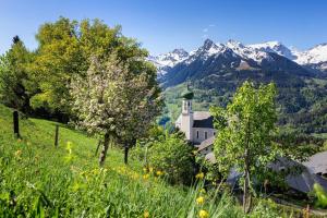 a church on a hill with mountains in the background at Haus Natalie in Bartholomäberg