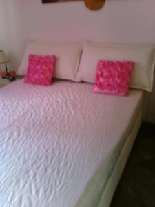 a white bed with pink pillows on top of it at Appartamento Libertà in Portovenere