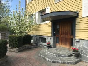 a yellow house with a wooden door and flowers in pots at BoSmart Apartments in Gothenburg +19 photos