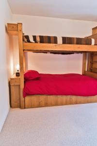 a bedroom with a wooden bunk bed with red sheets at Chesa Gulas - La Punt-Chamues-ch in La Punt-Chamues-ch