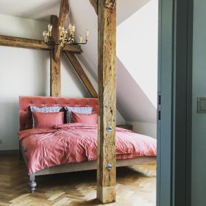 a bedroom with a bed with red sheets and a chandelier at Beautiful apartments - Romantic in Liepāja