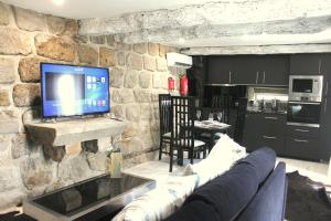 a living room with a couch and a tv on a stone wall at Casa do Largo do Cais in Vila Nova de Cerveira