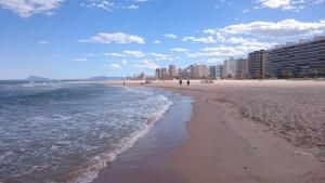 plaża z ludźmi chodzącymi po piasku i oceanie w obiekcie Apartment Joanna Grau de Gandia w mieście Los Mártires