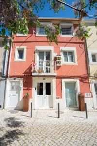 a red building with white doors and a balcony at Apartamento Troino in Setúbal