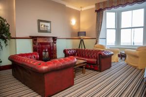 a living room with red leather furniture and a fireplace at Royal Lion Hotel in Tenby