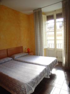 a bedroom with two beds and a large window at Hostal Adarnius in La Bisbal