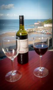 Una botella de vino y dos copas en una mesa con la playa en Royal Lion Hotel, en Tenby