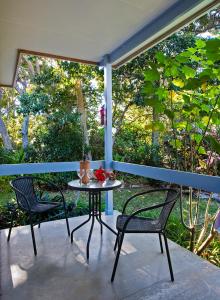 uma mesa e duas cadeiras num alpendre com uma janela em The Broken Banyan em Lord Howe