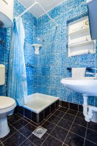ein blau gefliestes Badezimmer mit Waschbecken und Toilette in der Unterkunft Sea View Apartments Pericic in Sukošan + 37 Fotos