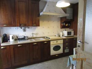 a kitchen with wooden cabinets and a stove and a microwave at Casa do Ti Messias in Almeida