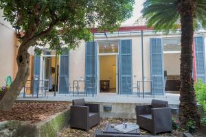patio z niebieskimi okiennicami i krzesłami oraz palmą w obiekcie La Casa Di Flora w mieście Napoli
