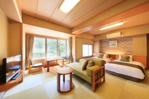 Shimobe Hotel في Minobu: غرفة نوم بسرير واريكة وتلفزيون