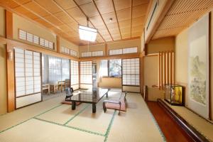Shimobe Hotel في Minobu: غرفة معيشة مع طاولة وكراسي ونوافذ