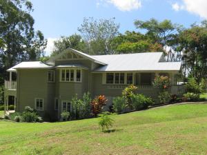 a green house with a white roof at Keillor Lodge in Maleny