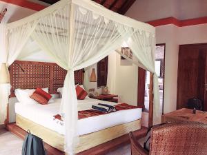 a bedroom with a canopy bed with white curtains at Puri Dajuma Beach Eco-Resort & Spa in Pulukan