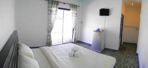 a room with a white bed with a window at Wangthong Beach Resort in Laem Sing