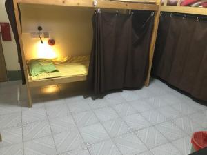 Cama pequeña en habitación con cortina en Kwangchowan Hostel, en Zhanjiang