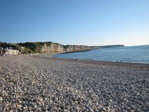 a rocky beach with people walking on the water at Le quai Sud in Fécamp