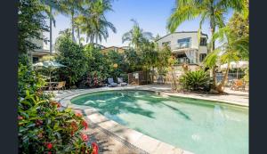 una piscina en un patio con palmeras en Aarons Luxury Retreat, en Noosaville