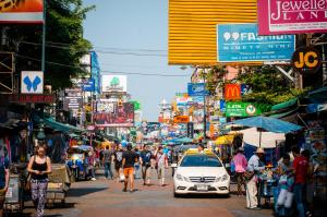 een drukke straat met mensen die lopen en een auto op straat bij Suneta Hostel Khaosan in Bangkok