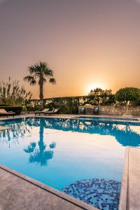 a swimming pool with a sunset in the background at Oceanides Luxury Apartments in Sitia