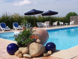 una piscina con sillas y sombrillas junto a una piscina en La Roulotte de la Vallée du Lot, en Le Temple-sur-Lot