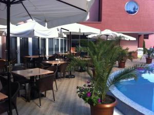 a restaurant with tables and umbrellas and a swimming pool at Hotel Opal in Sunny Beach