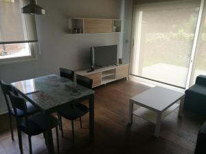 a living room with a table and a television at Apartamentos La Encina in Celorio