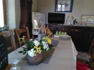 a dining room table with a vase of flowers on it at Le champ des étoiles in Massoulès