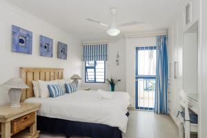a bedroom with a large white bed and blue curtains at Le Paradis 30 in Ballito