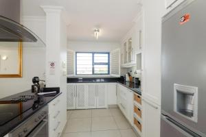 a white kitchen with white cabinets and a window at Le Paradis 30 in Ballito