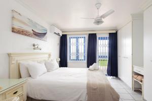 a white bedroom with a large white bed and windows at Le Paradis 5 - With Inverter in Ballito