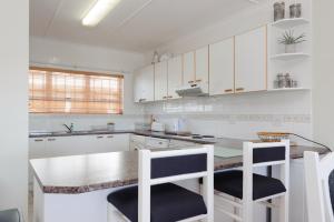 a kitchen with white cabinets and a counter with two stools at Long Island 11 - FAMILY ONLY in Ballito