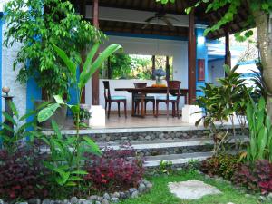 eine Terrasse mit einem Tisch, Stühlen und Pflanzen in der Unterkunft Villa Shantitara Bungalows in Sanur