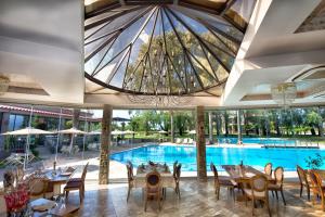 a dining room with a pool and a chandelier at Corali Resort in Agrinio