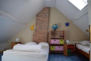 a attic room with two beds and a brick wall at La Métairie du Moulin de Meusnes in Meusnes