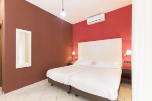 a bedroom with red walls and a white bed at Hotel La Baia in Bari