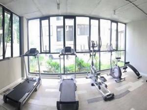 a gym with several tread machines in a room with windows at Izen Plus Budget Hotel & Residence in Rayong