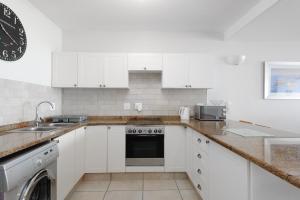 a white kitchen with white cabinets and a dishwasher at Suntrap 6 - FAMILY ONLY in Ballito