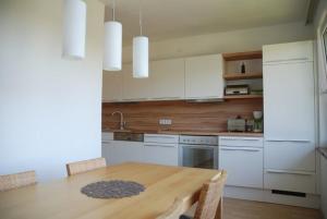 a kitchen with a wooden table and white cabinets at Apartment Sternentor in Engerwitzdorf