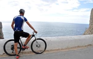 a man riding a bike near the ocean at Martinhal Sagres Beach Family Resort Hotel in Sagres