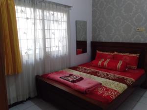 Un dormitorio con una cama con sábanas rojas y una ventana. en Puri Garden Batu, en Batu