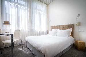 a bedroom with a large white bed and a desk at Hotel d'Angleterre in Avignon