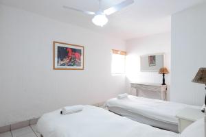 two beds in a room with white walls at Skiathos 8 - FAMILY ONLY - Max 6 adults and 2 children in Ballito