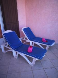 - deux chaises bleues et blanches avec des serviettes roses dans l'établissement Villa Victoria, à Trou dʼ Eau Douce
