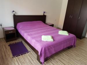 a bedroom with a purple bed with two towels on it at S&G Apartment in Vranje