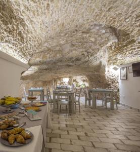 ein Esszimmer mit Tischen und einer Steinmauer in der Unterkunft Casa dell'Aromatario b&b in Sciacca