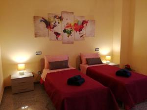two beds in a room with red sheets at Frate E Soru in Cannole