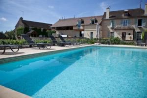 a swimming pool with chairs and a house in the background at Domaine VIOLOT-GUILLEMARD in Pommard