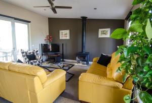 a living room with a yellow couch and a fireplace at Corrugated Cottage in Dunkeld